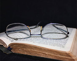 A pair of glasses laying on an open book.